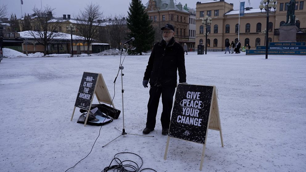 Man på torg med fredsskyltar