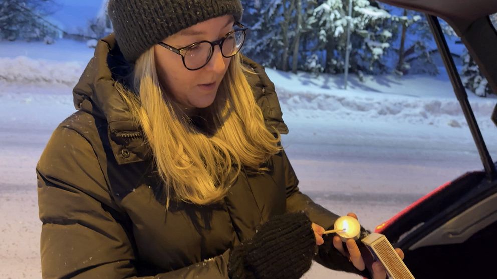 SVT:s reporter Stina Ahlinder tänder ett värmeljus vid bilen efter vägen.