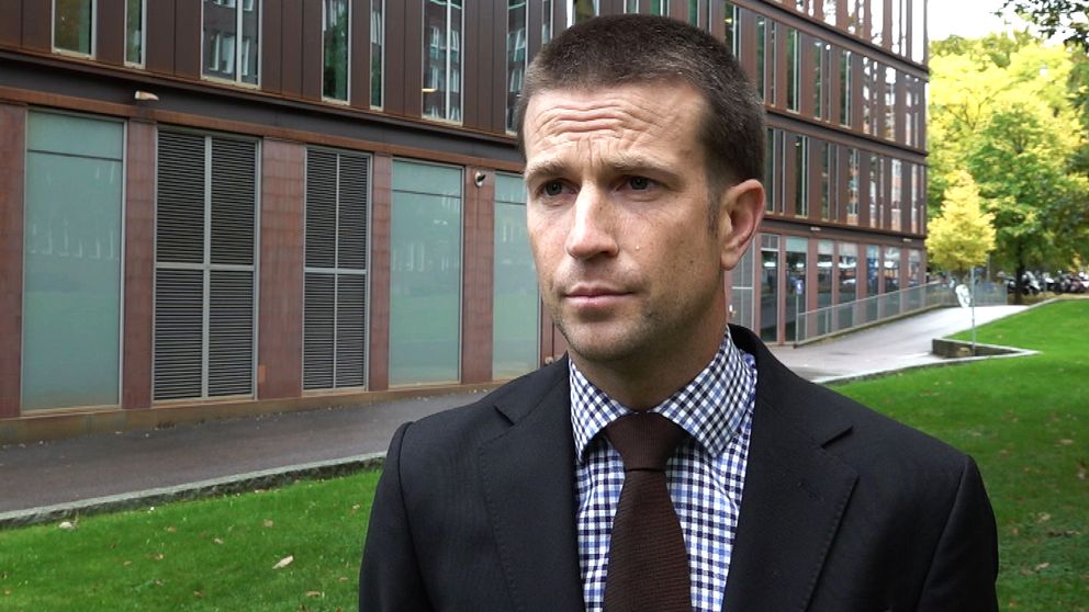 Åklagare Viktor Törneke om kopplingen mellan ett grovt vapenbrott i Göteborg och skjutningen på Kungsmässan. Bakgrunden visar en grön gräsmatta och träd som bidrar till en urban miljö.