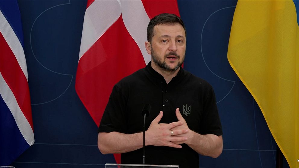 Ukrainas president Volodymyr Zelenskyj med flaggor i bakgrunden