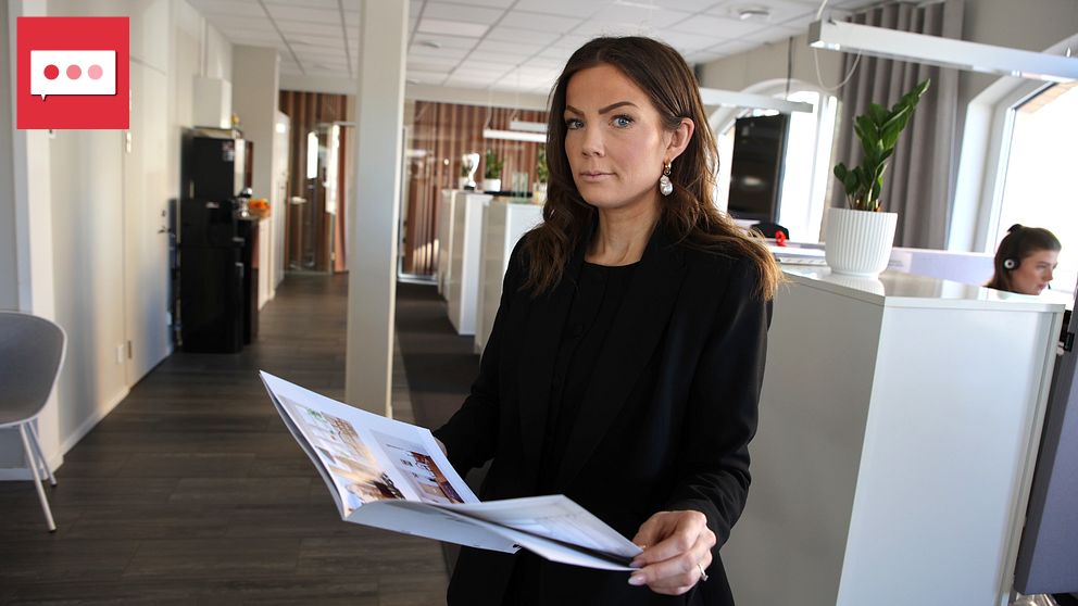 Person läser broschyr i ett kontor med modernt inredda arbetsplatser.