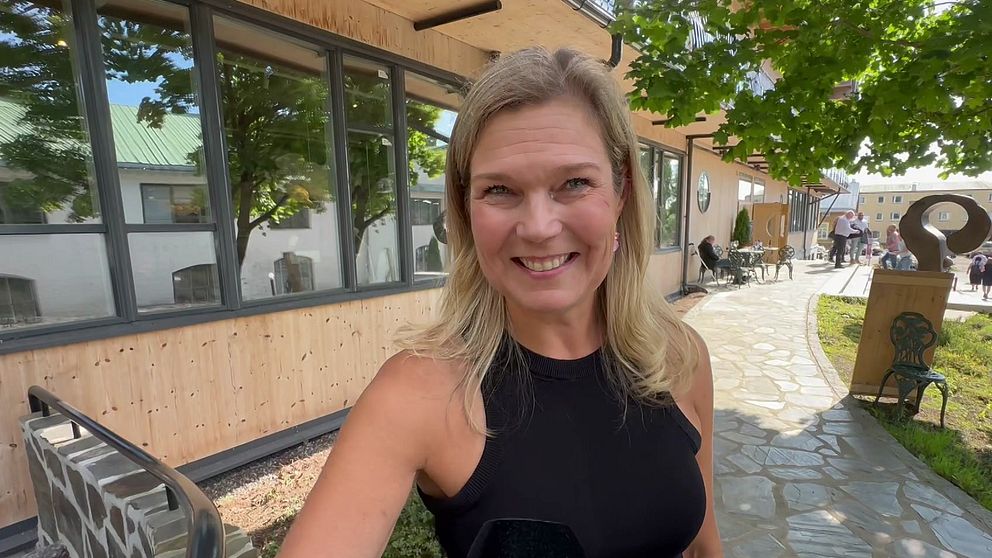 Blond kvinna tittar in i kameran och ler.