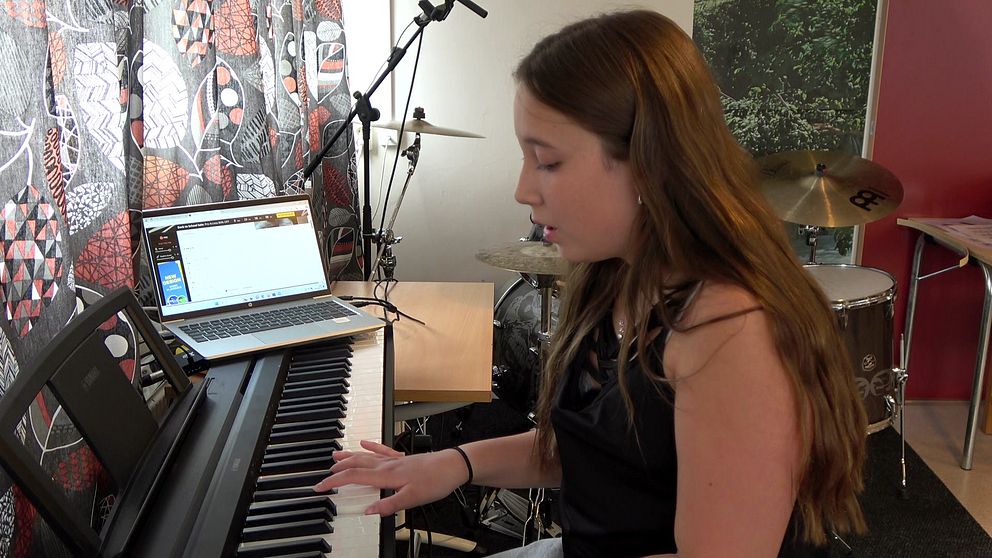 Lilly Sundström i svart linne på kulturskolan i Arjeplog. Hon sitter och spelar piano framför en dataskärm.