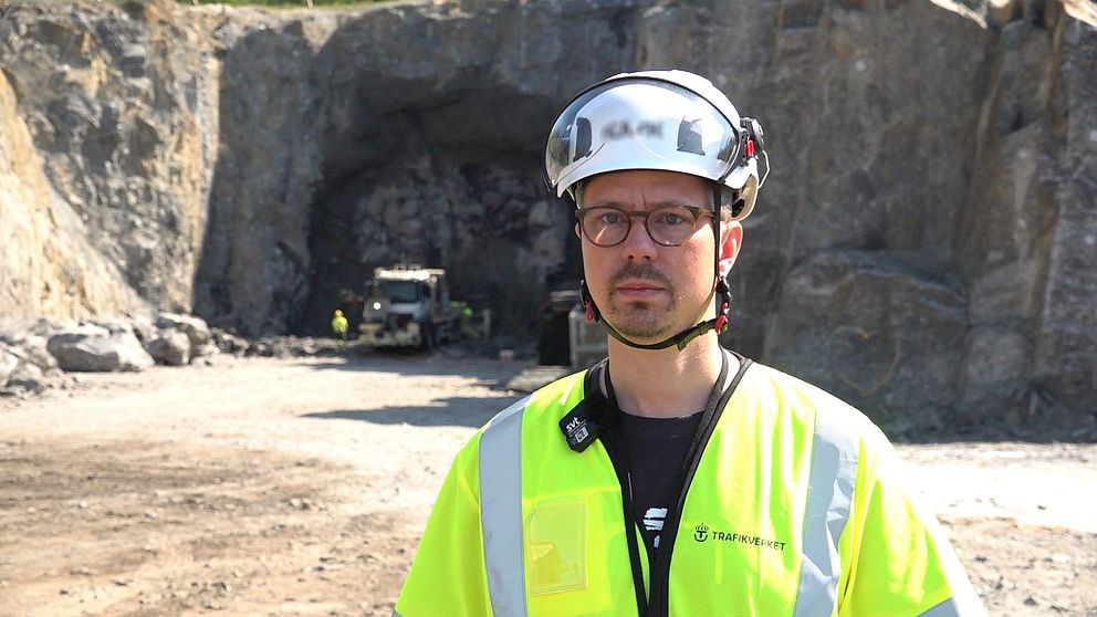 Man i hjälm står före tunnelbygget vid Ersmarksberget.