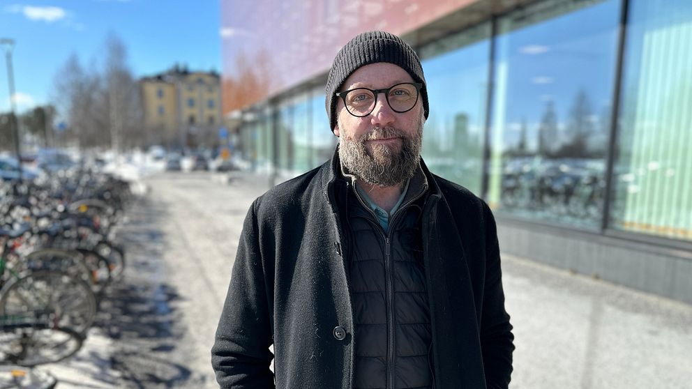 Joakim Åström i svart mössa, svart jacka och glasögon. Utanför Umestan i Umeå.
