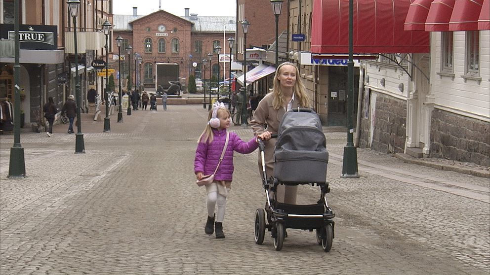 Mamma och barn med barnvagn går på stan