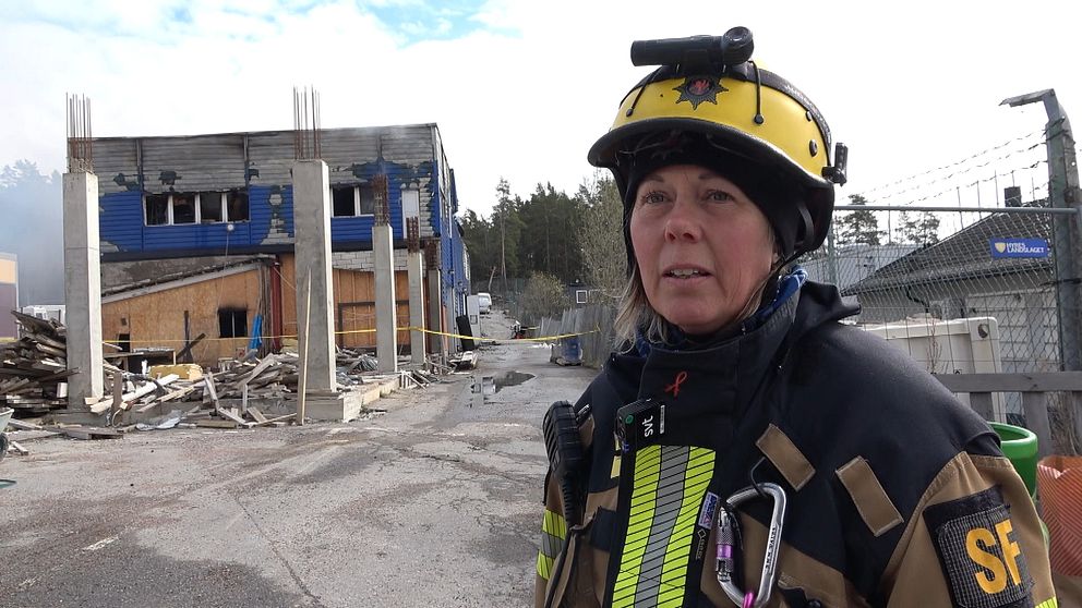 En brandman står framför en industrilokal i Södertälje som brinner.