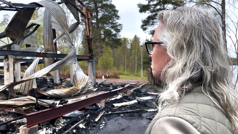 en gråhårig kvinna, Lina Kihlmark, står och tittar på en dansbana som brunnit ned till grunden.