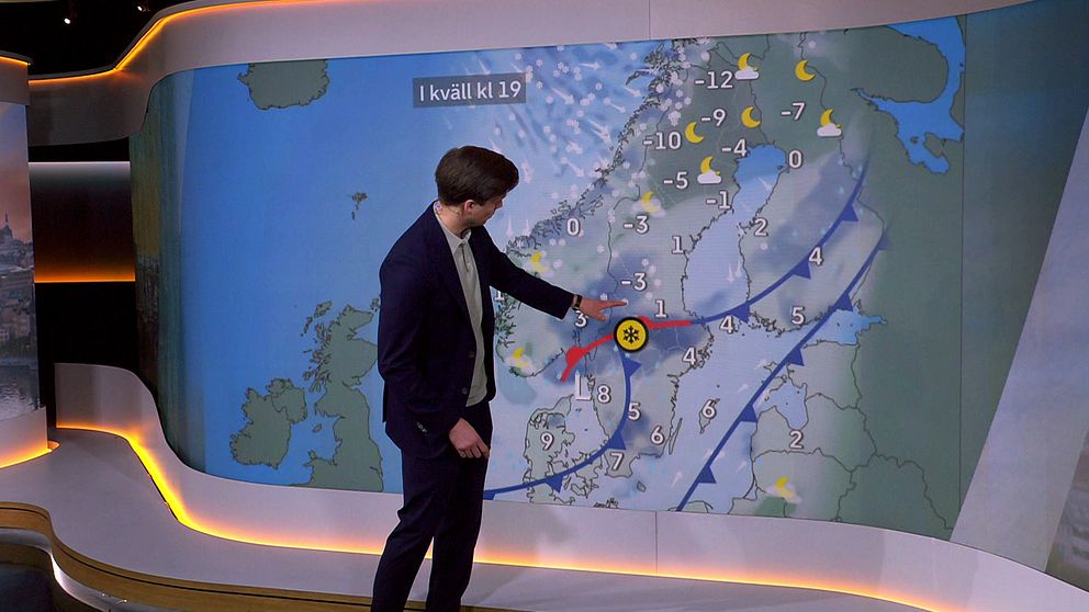 Vädret som presenteras av meteorolog Nils Holmqvist i SVT:s Morgonstudion, som pekar på en väderkarta över Sverige. Kartan visar temperaturen i olika områden, med siffror mellan -12 och 4 grader. Det finns också symboler för väderförhållanden, inklusive moln och snö. En röd linje markerar en kallfront och en gul solsymbol indikerar klart väder. Texten ”I kväll kl 19” anges högst upp på kartan.