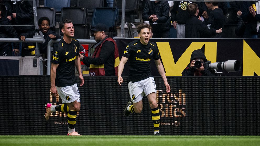 Två AIK-spelare firar ett mål inför jublande supportrar på fotbollsstadion.