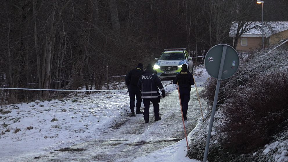 Tre poliser går mot polisbilen som står på den avspärrade platsen efter polisattacken på Österängen i Jönköping.