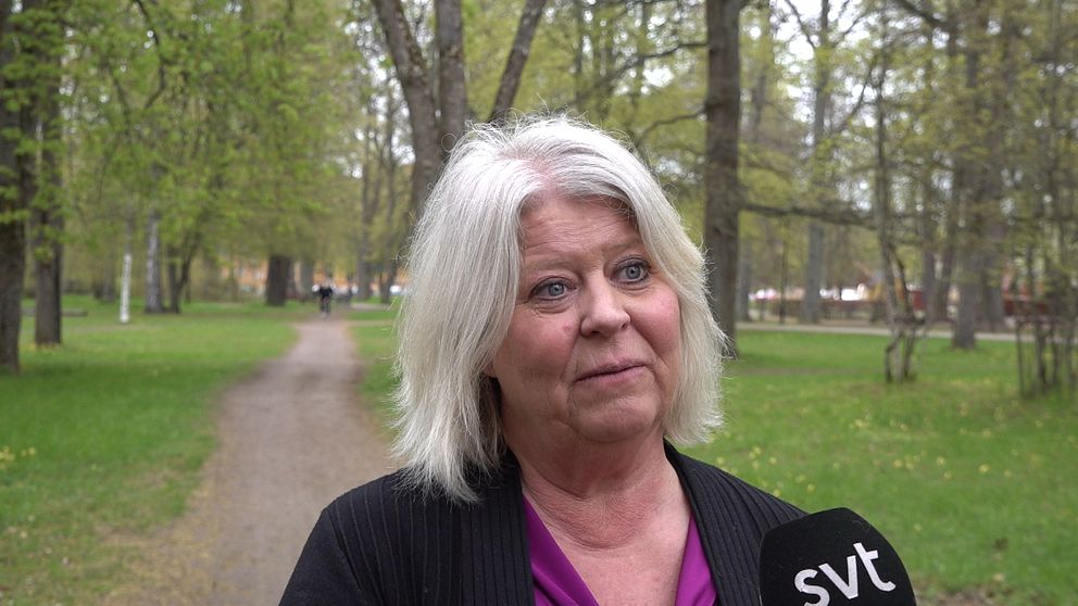 En kvinna intervjuas av SVT i en lummig park med grusgång och träd i bakgrunden.