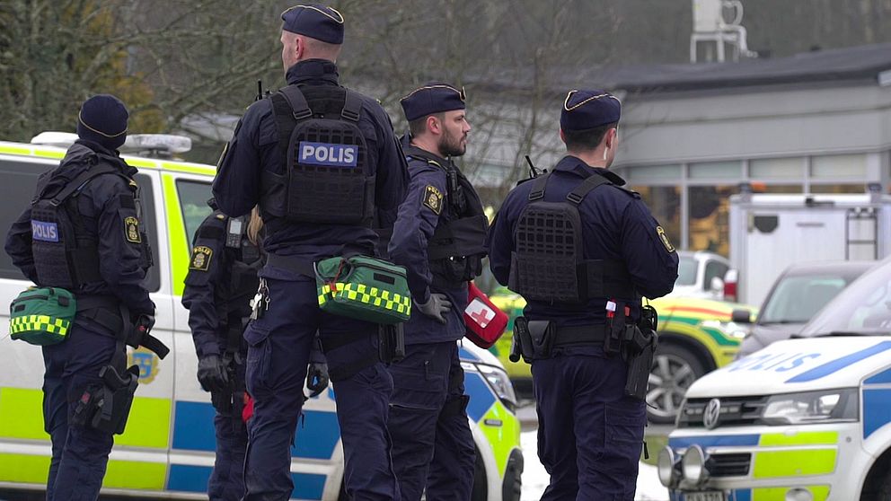Fem polise står vid två polisbilar utanför den drabbade skolan i Örebro där flera människor sköts till döds i februari 2025.