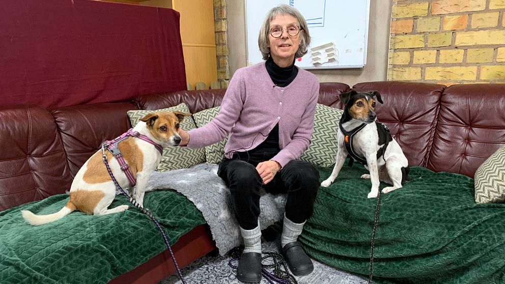 Hundinstruktören Pia Bildt Ström sitter i en soffa med sina två hundar