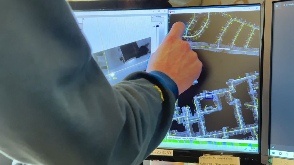 En person arbetar vid en dator och navigerar en kartapplikation som visar ett vattendrag med inritade vägar eller kanaler. Fingret pekar på skärmen där detaljer om området visas, vilket tyder på en analys eller övervakning av miljö eller infrastruktur.
