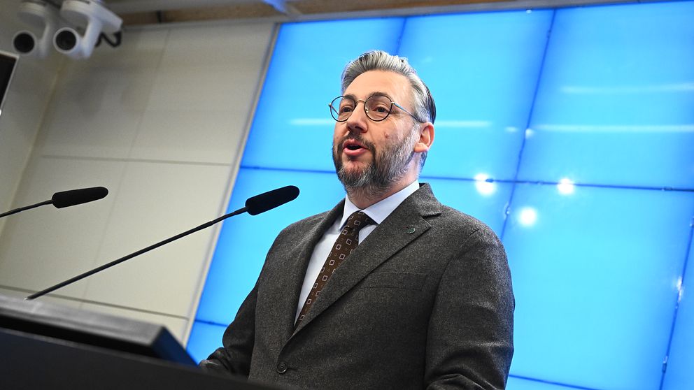 Man i kostym står vid podie med mikrofon framför blå bakgrund.  Centerpartiets partiledare Muharrem Demirok meddelar under en pressträff på måndagen att han kommer att avgå.