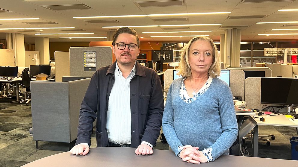 Två personer står vid ett bord i en kontorsmiljö.