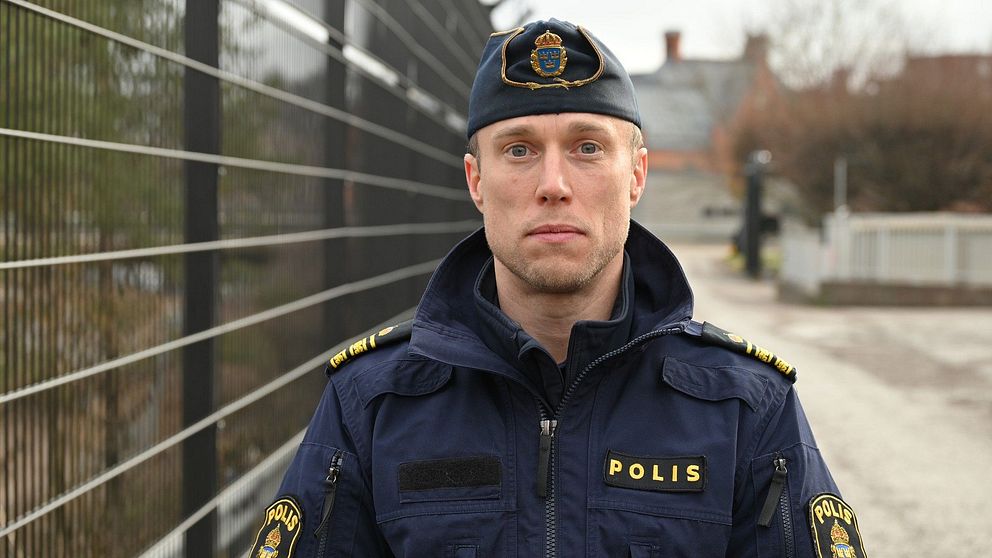 Polis i uniform vid stängsel på en mulen dag.