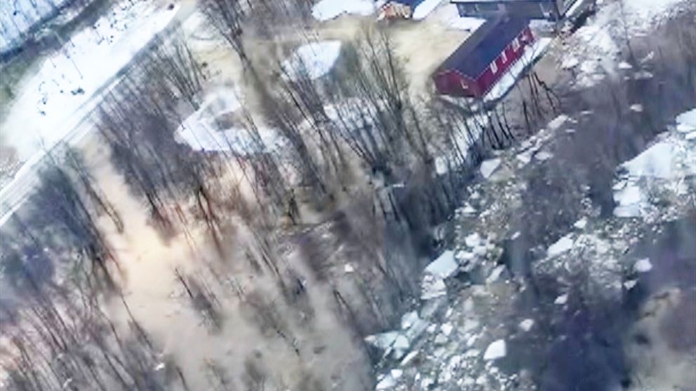 Flygbild på en översvämning på grund av ispropp i Tärnaby. Ett skogsområde med ett rött hus vid vattenbrynet. Träd omges av vatten och isflak syns flyta i översvämningsvattnet.