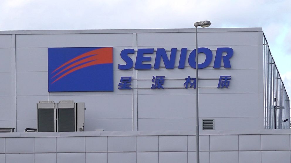 Företagsbyggnad med ”Senior” logotyp och kinesiska tecken på fasaden.