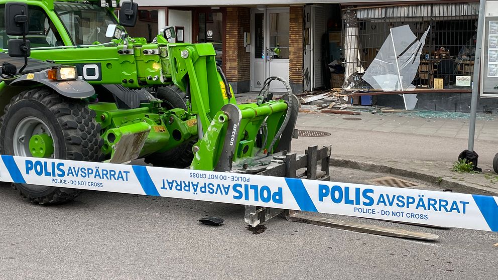 Polisavspärrning vid en trasig butikslokal, grön traktor framför förstörd entré.