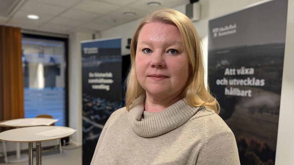 Ida Rönnblom står mitt i ett konferensrum i Skellefteå kommuns stadshus. I bakgrunden syns två att Skellefteå kommuns roll-ups som marknadsför kommunen.