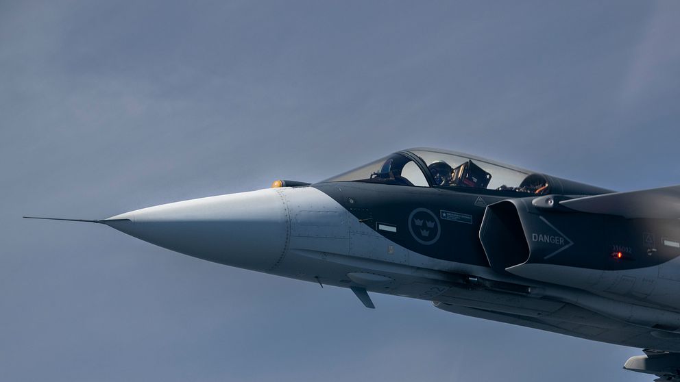 Svenskt stridsflygplan JAS Gripen i luften mot klar himmel.