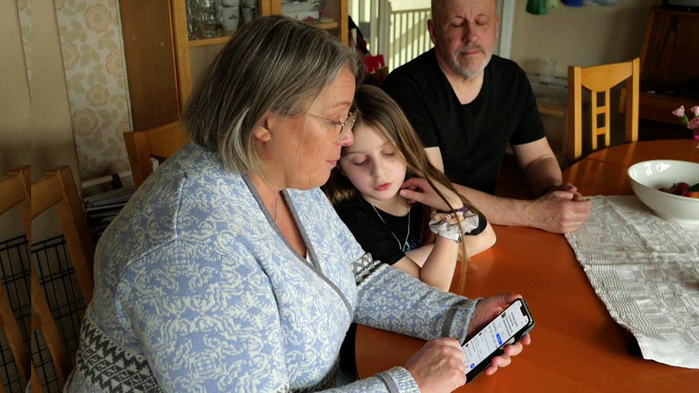 Lisa, 9, och hennes fosterhemsföräldrar runt ett bord.