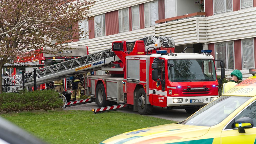 Brandbil och ambulans står utanför ett lägenhetshus där det har brunnit.