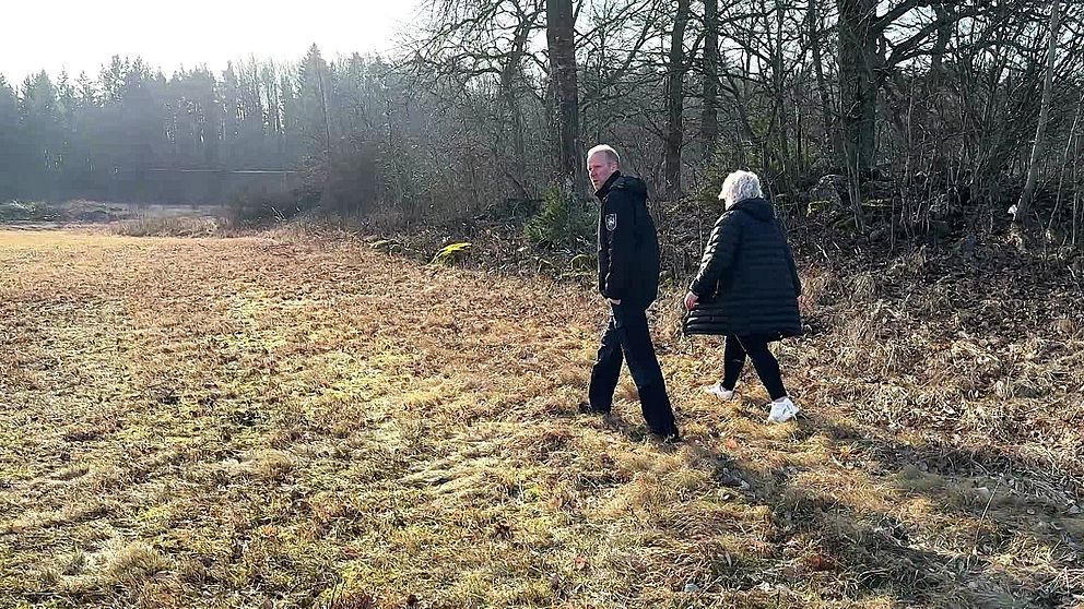 Två personer promenerar genom en höstlik skogsdunge.