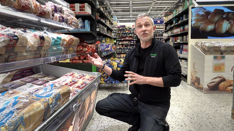 Markus Wahlgren sitter bredvid brödhyllor i en livsmedelsbutik.