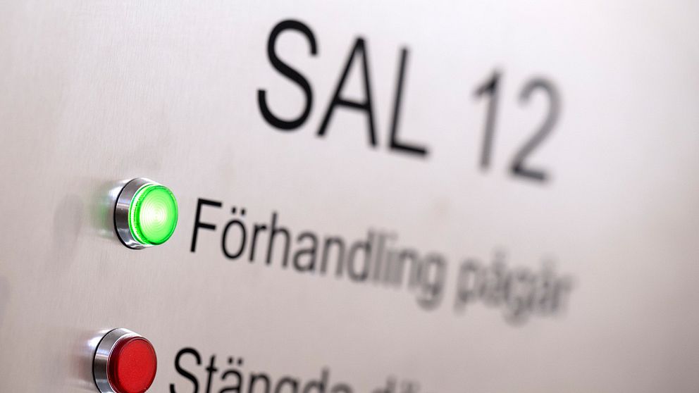 En skylt utanför en rättegångssal som informerar att förhandling pågår med ett tänt grönt ljus.