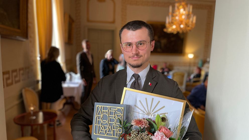 David Lundgren poserar med blommor och priser efter att ha vunnit årets unga företagare.
