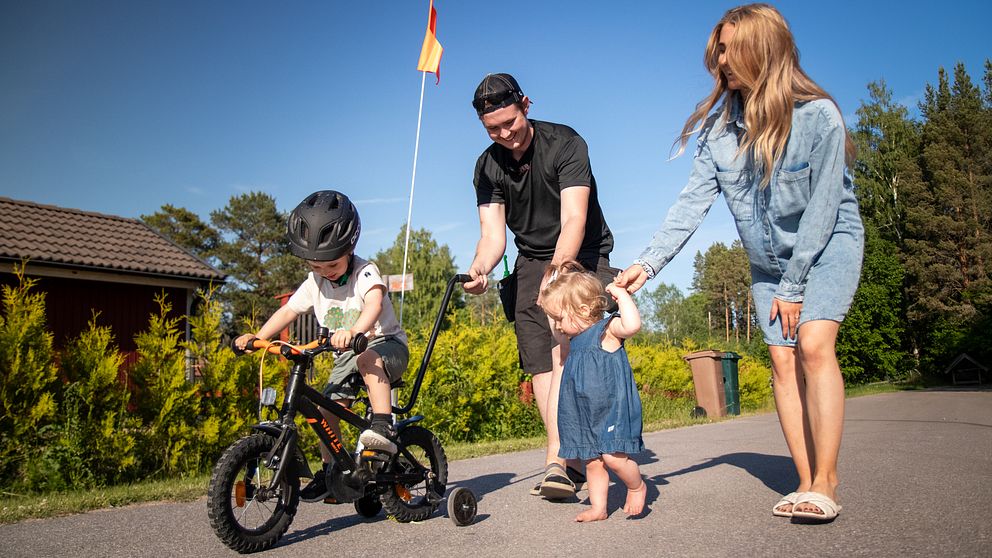 Småbarnsföräldrarna William och Vilma hjälper sina barn att cykla och gå på en väg bredvid familjens hus