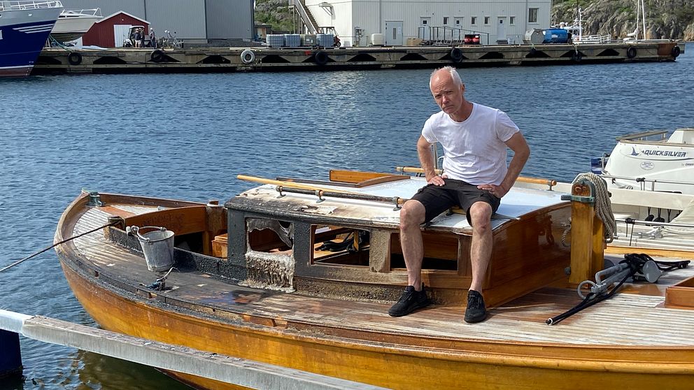 man i shorts och t-shirt sitter på en ldhärjar träbåt
