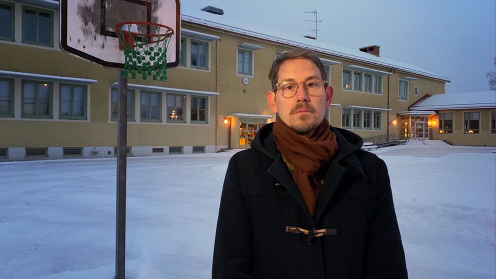 En politiker står på en skolgård i dalarna och tittar in i kameran