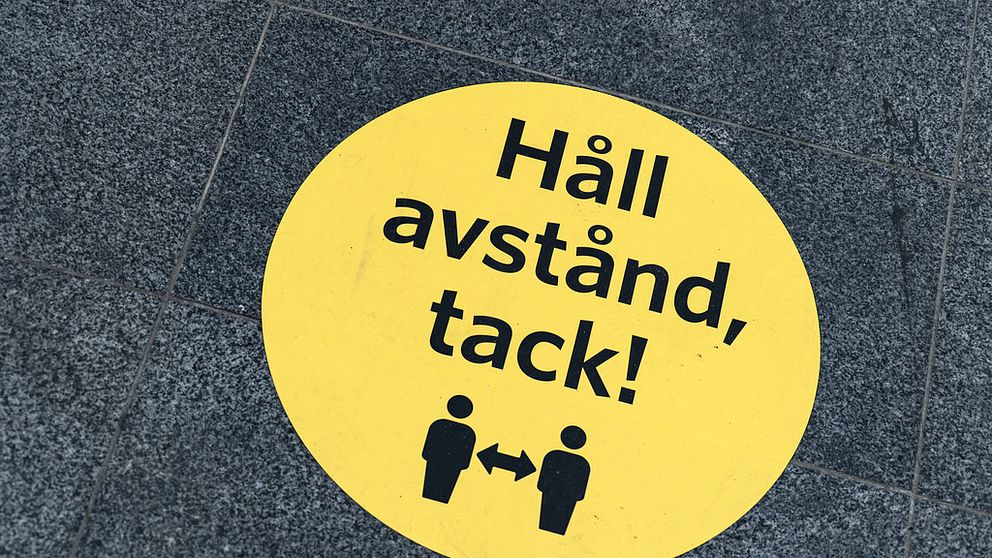 En dekal på ett golv där det står ”Håll avstånd, tack”
