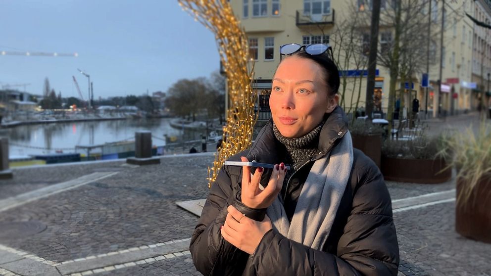SVT:s reporter står och håller i sin mobiltelefon