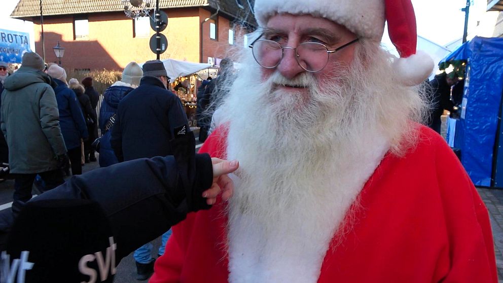 SVT:s reporter sträcker fram handen för att känna om tomtens skägg är äkta eller inte.