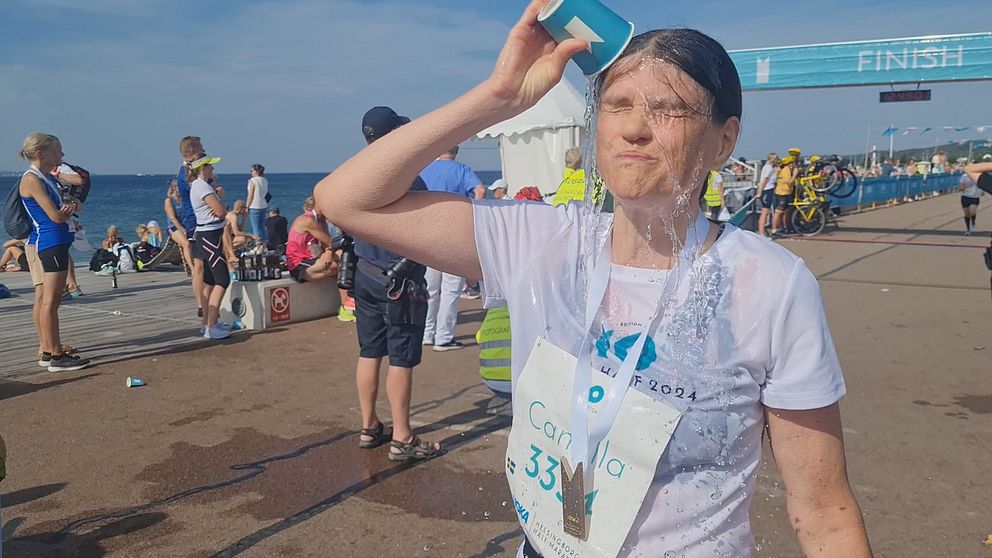Maratonlöpare häller vatten över ansiktet