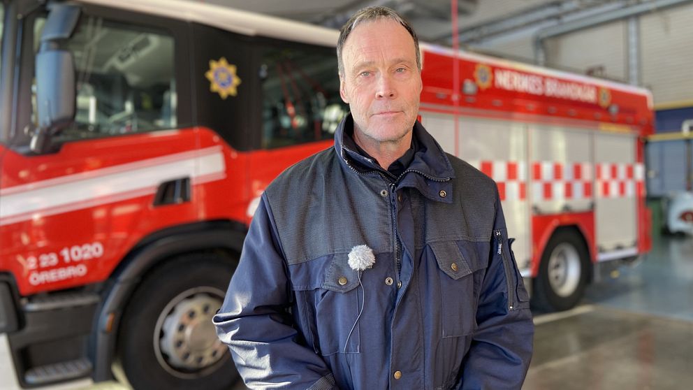 Vice brandchef Nerikes brandkår. En man står framför en brandbil i ett garage.