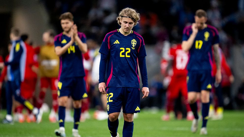 Svenska fotbollsspelare i mörka uniformer går besvikna av planen.