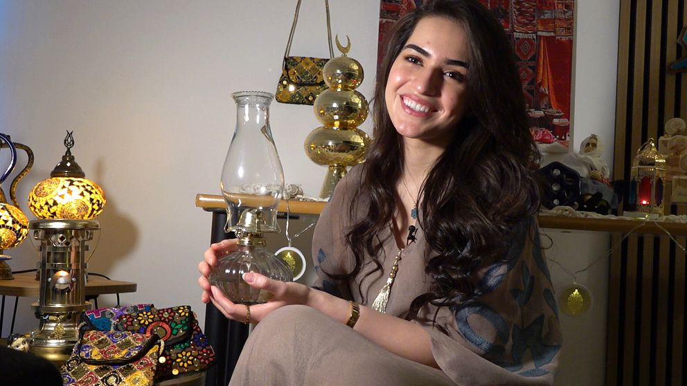 Maryam Al-Ameri sitter och håller i en lampa av glas.