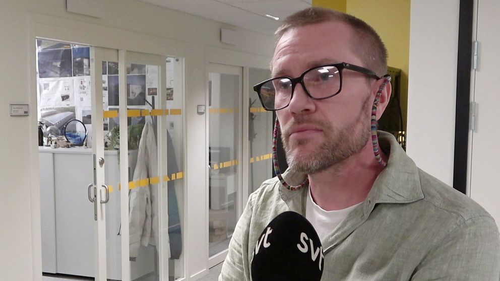 Henrik Mattsson, vd på företaget Titan står i ett kontorsutrymme och intervjuas av SVT. I bakgrunden syns glasdörrar som leder till ett annat rum, och där är också klädesplagg och kontorsmaterial synligt. Väggarna är målade i ljusa färger och rummet är väl upplyst.