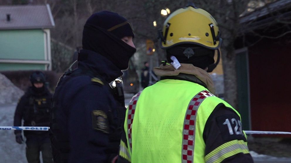 En polis och en person från räddningstjänsten står vid avspärrningarna vid explosionen i Strängnäs.