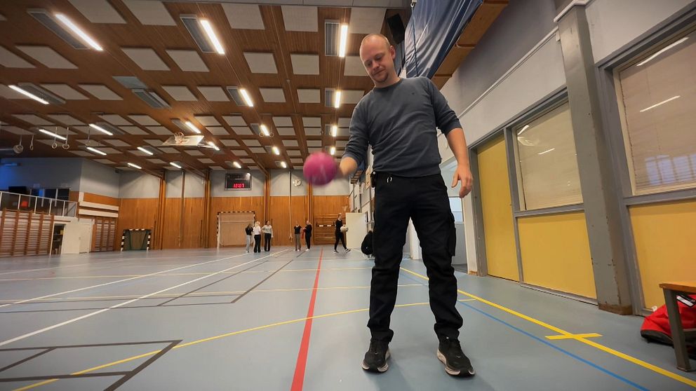 Johan Persson, ordförande i Torsby IK, står i en sporthall med en studsande boll i förgrunden.