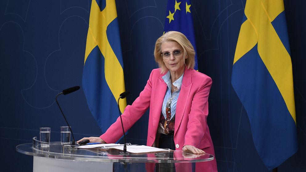 Elisabeth Svantesson (M) vid podium framför svenska och EU flaggor.