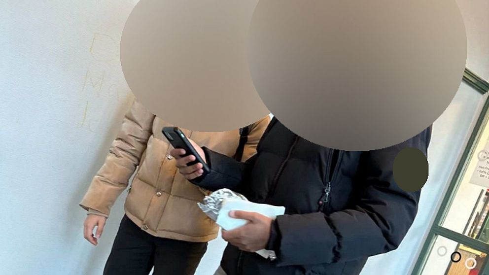 Två pojkar tittar på en mobil. Deras ansikten är censurerade.
