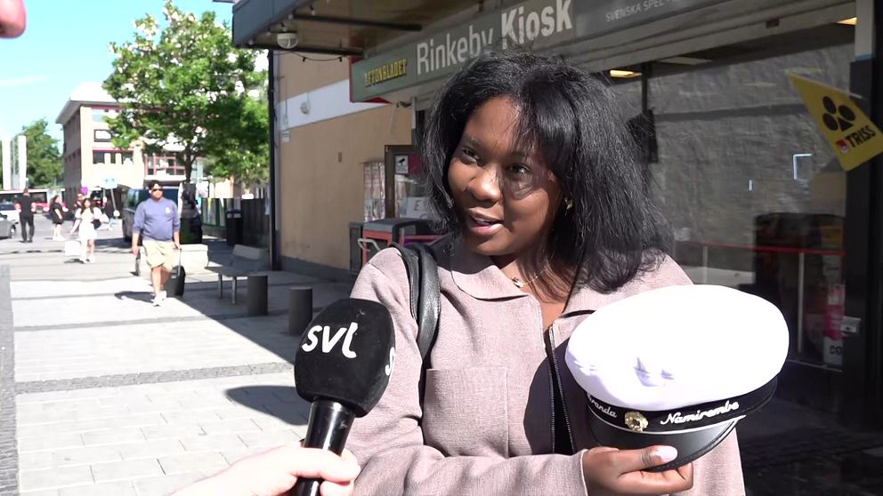 Tjej med studentmössa utanför Rinkeby kiosk.