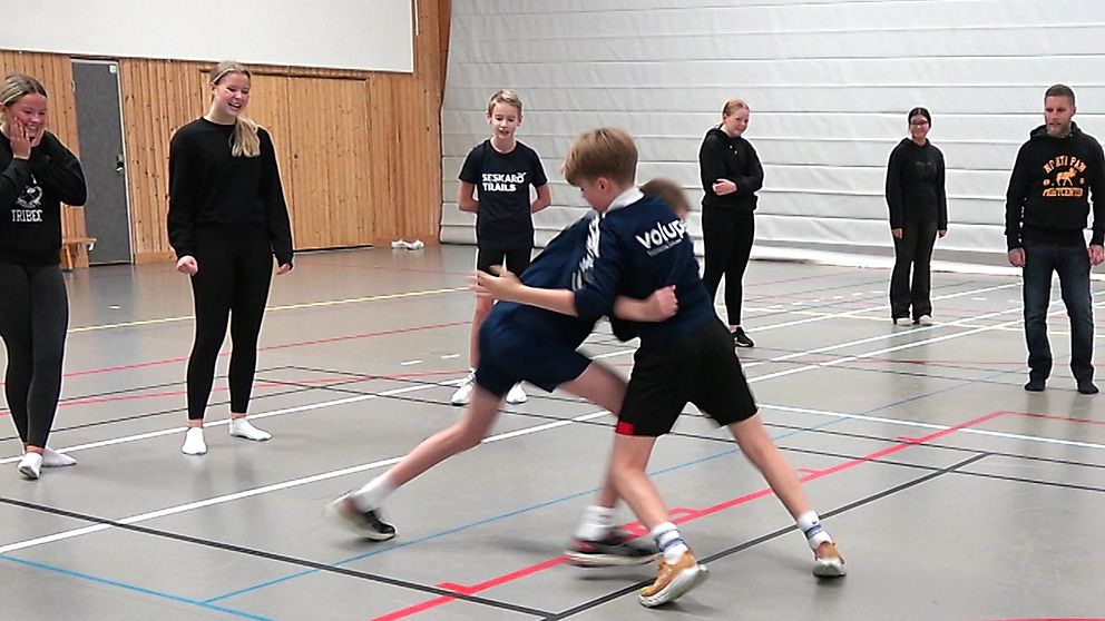 Två skolelever i Luleå tränar ”kamplek” medan lärare och elever tittar på.
